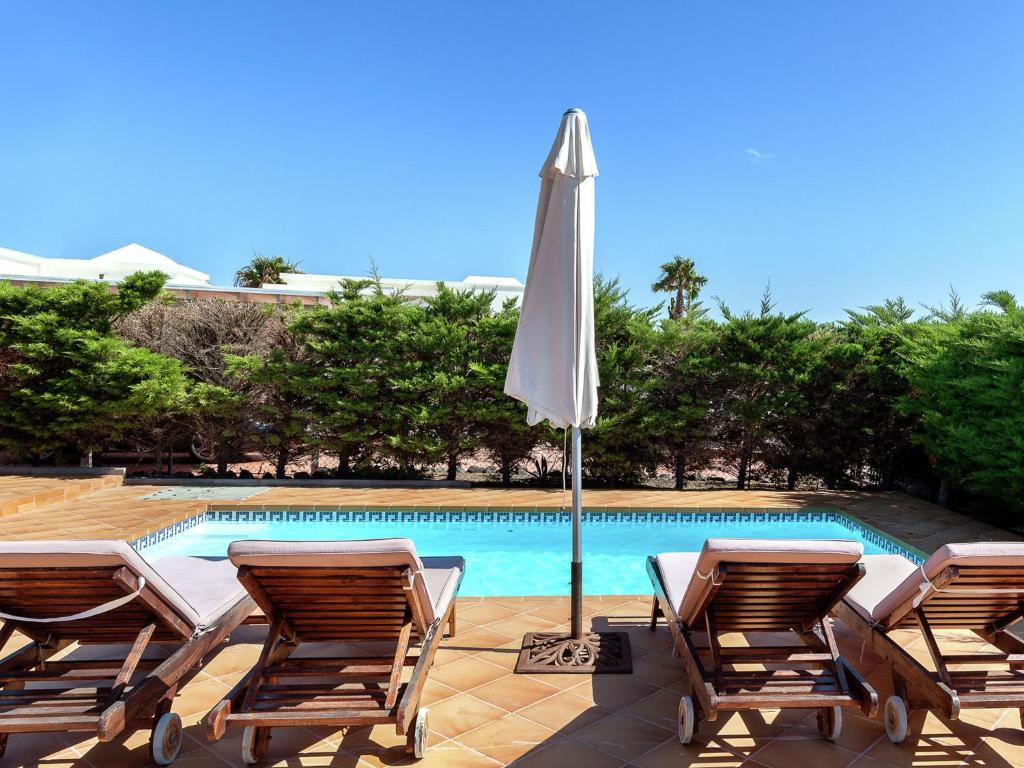 a group of chairs and an umbrella next to a pool at Belvilla by OYO Mango II 6 pax in Playa Blanca