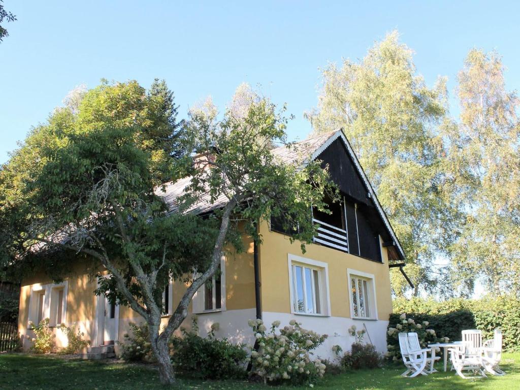 una casa con un árbol delante de ella en An eight person holiday home on a 1600 hectare, en Tachov