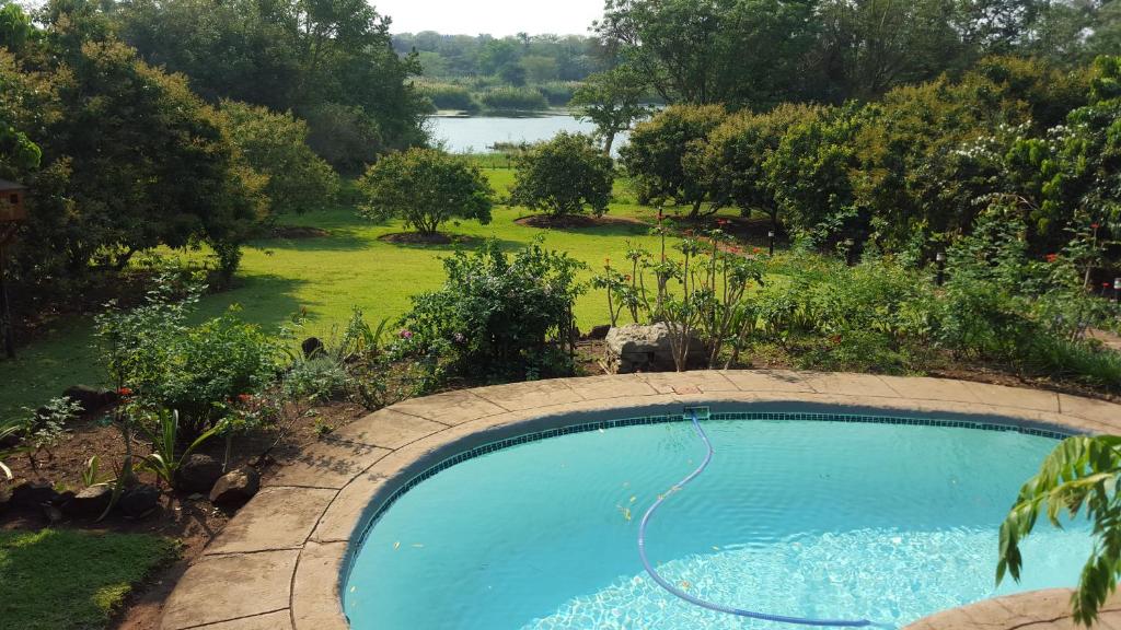 a swimming pool in a yard with a field and a lake at Orchards Farm Cottages in Komatipoort