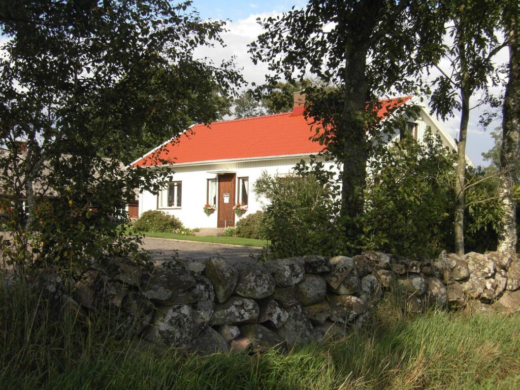 uma casa branca com um telhado vermelho e uma parede de pedra em Hermanslycke Bed & Breakfast em Tvååker