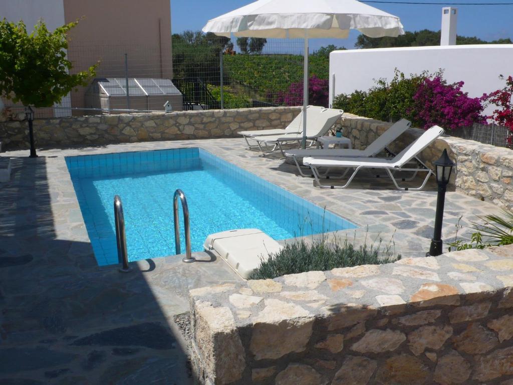 een zwembad met 2 stoelen en een parasol bij Stylish Villa in Loutra in Loutra