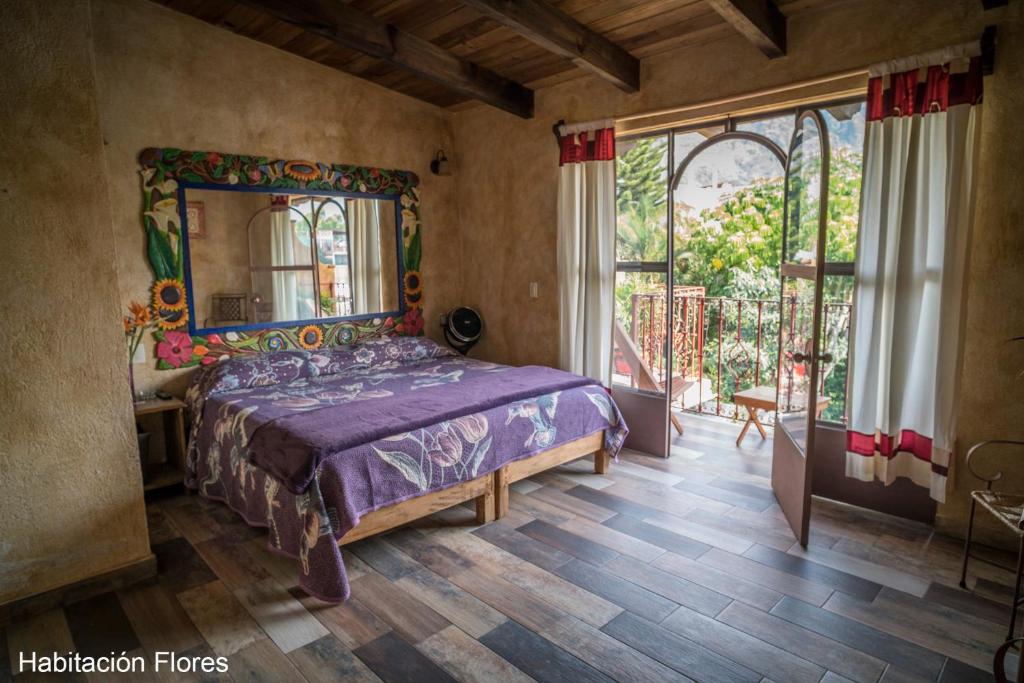 a bedroom with a bed and a large window at Flor de Cera in Tepoztlán