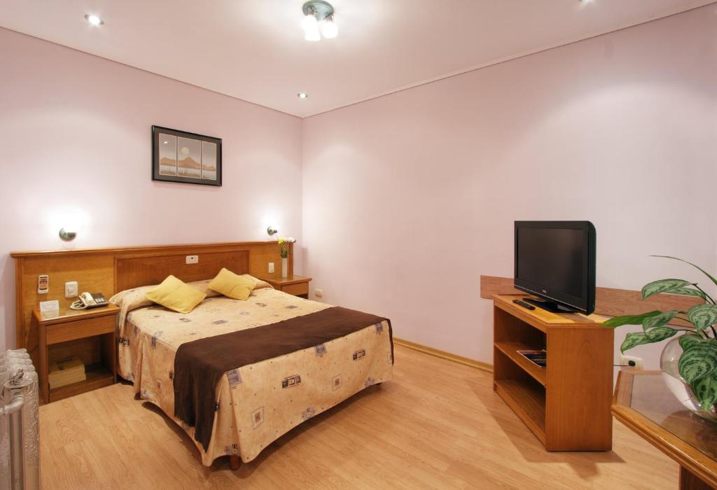 a bedroom with a bed and a flat screen tv at Gran Hotel De La Paix in Buenos Aires