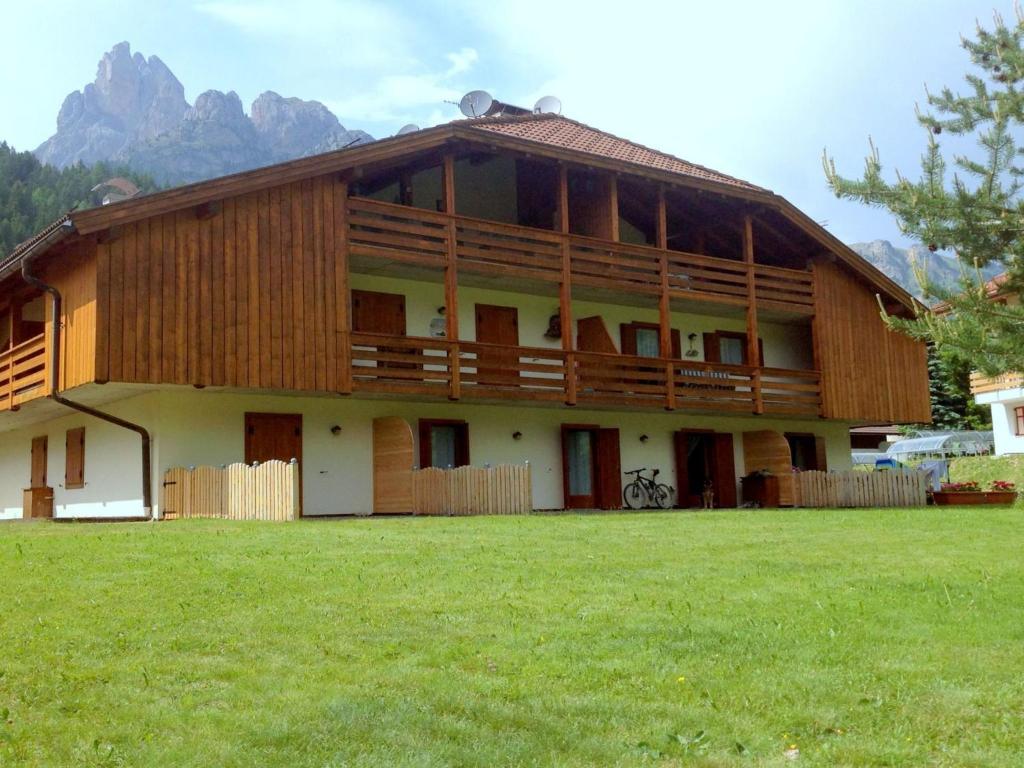 a large wooden house with a grass field at Lovely Chalet in Pozza di Fassa with Garden in Pozza di Fassa