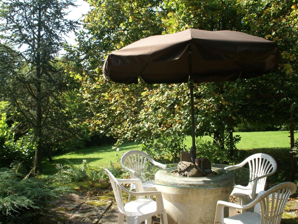 une fontaine en pierre avec des chaises et un parasol dans l'établissement Holiday home near Chapelle Aux Bois, à Bains-les-Bains