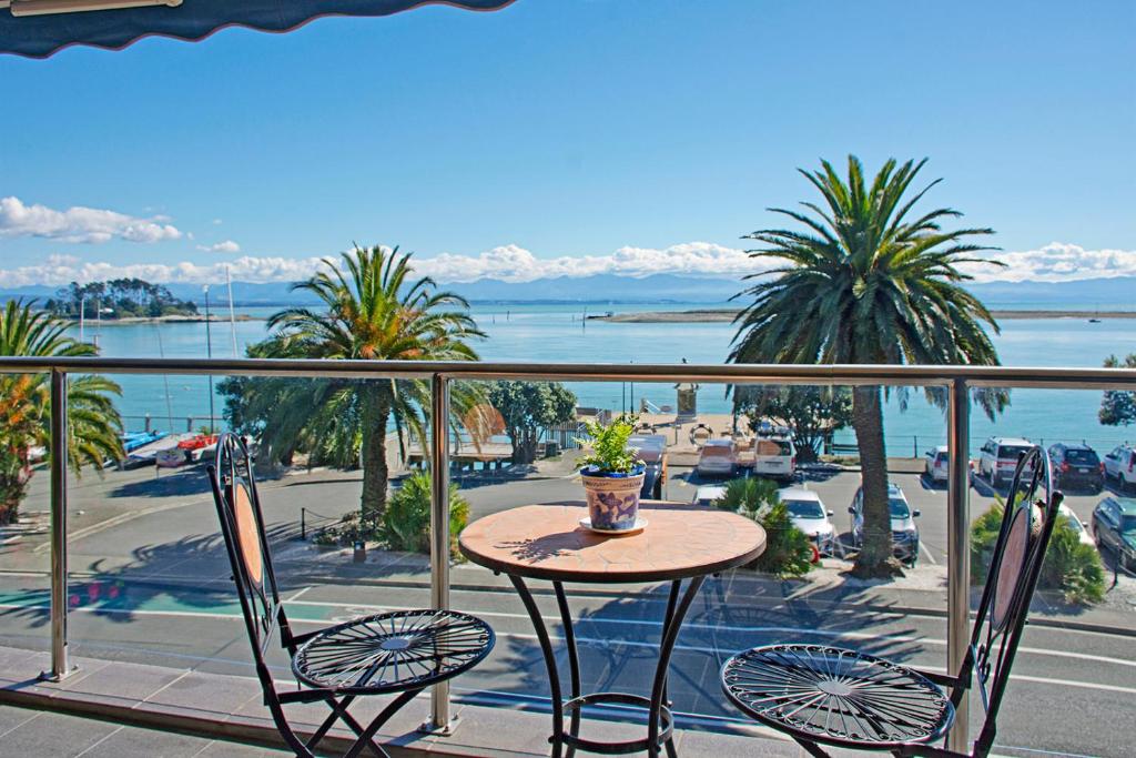 einen Tisch und Stühle auf einem Balkon mit Meerblick in der Unterkunft Waterfront Escape in Nelson