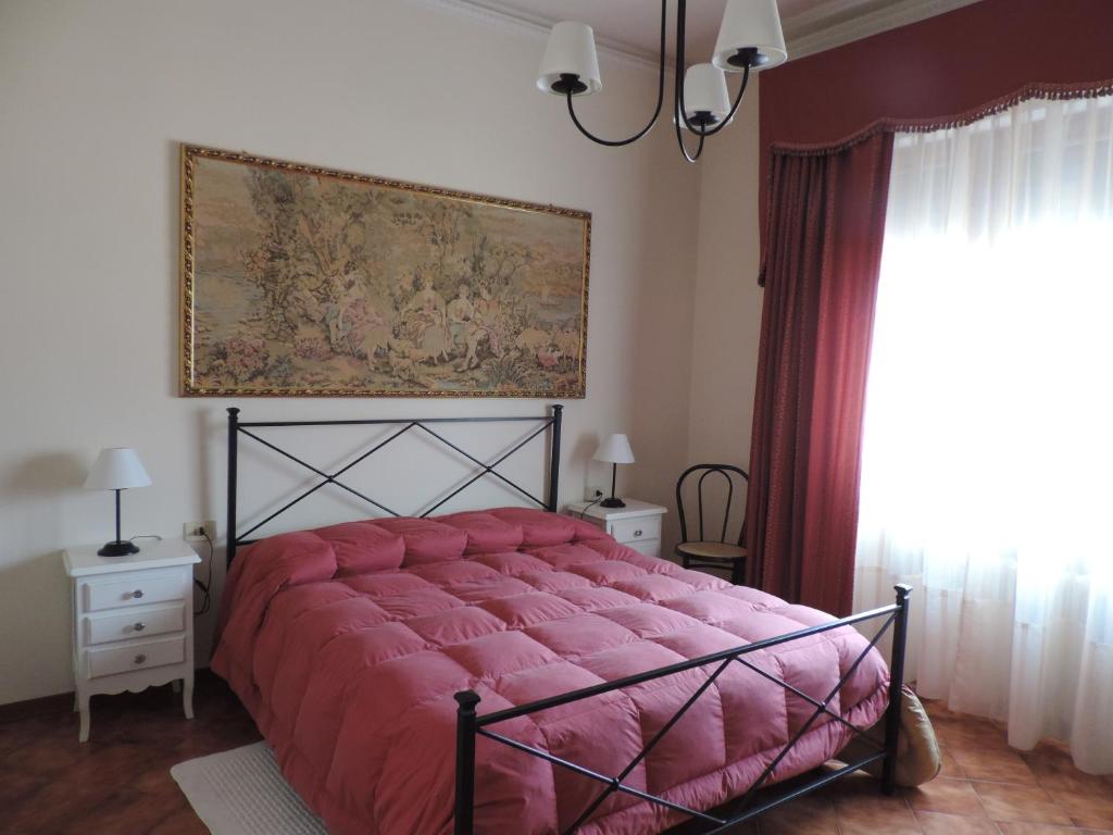 Chiantirooms Guesthouse في غريفي ان شنتي: غرفة نوم بسرير احمر مع لوحة على الحائط