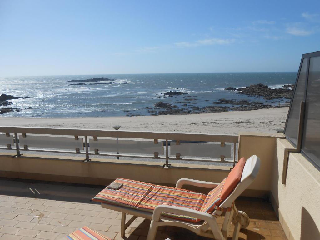 een tafel en een stoel op een balkon met uitzicht op het strand bij Casa na Praia do Mindelo in Mindelo