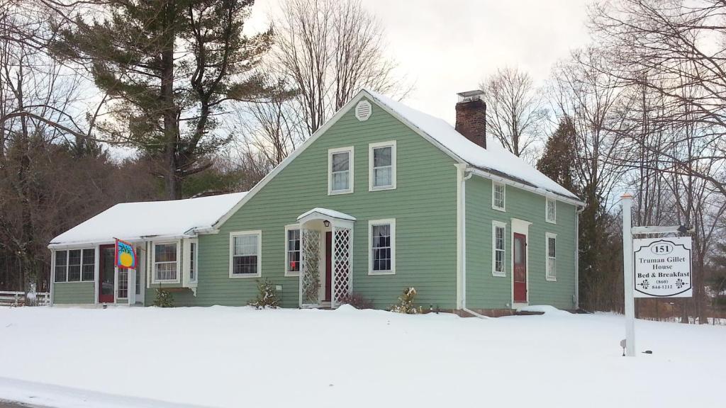 Granby的住宿－Truman Gillet House B & B，一座绿色房子,上面有雪