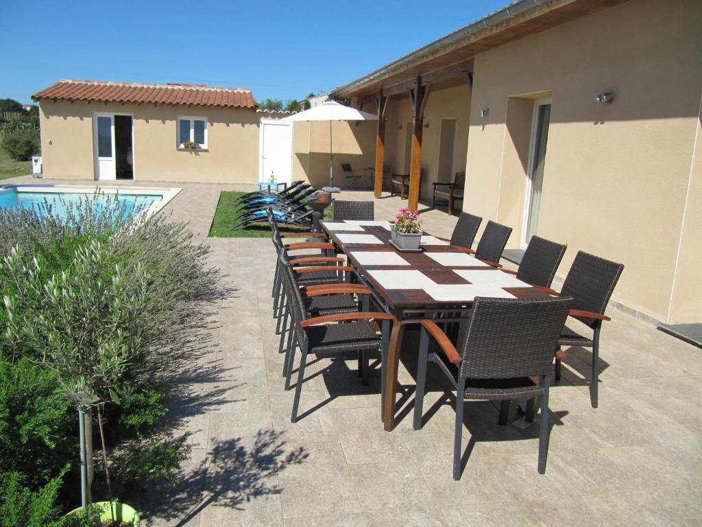 eine Terrasse mit einem Tisch und Stühlen neben einem Pool in der Unterkunft Luxury villa with pool in Thermes Magnoac in Thermes-Magnoac