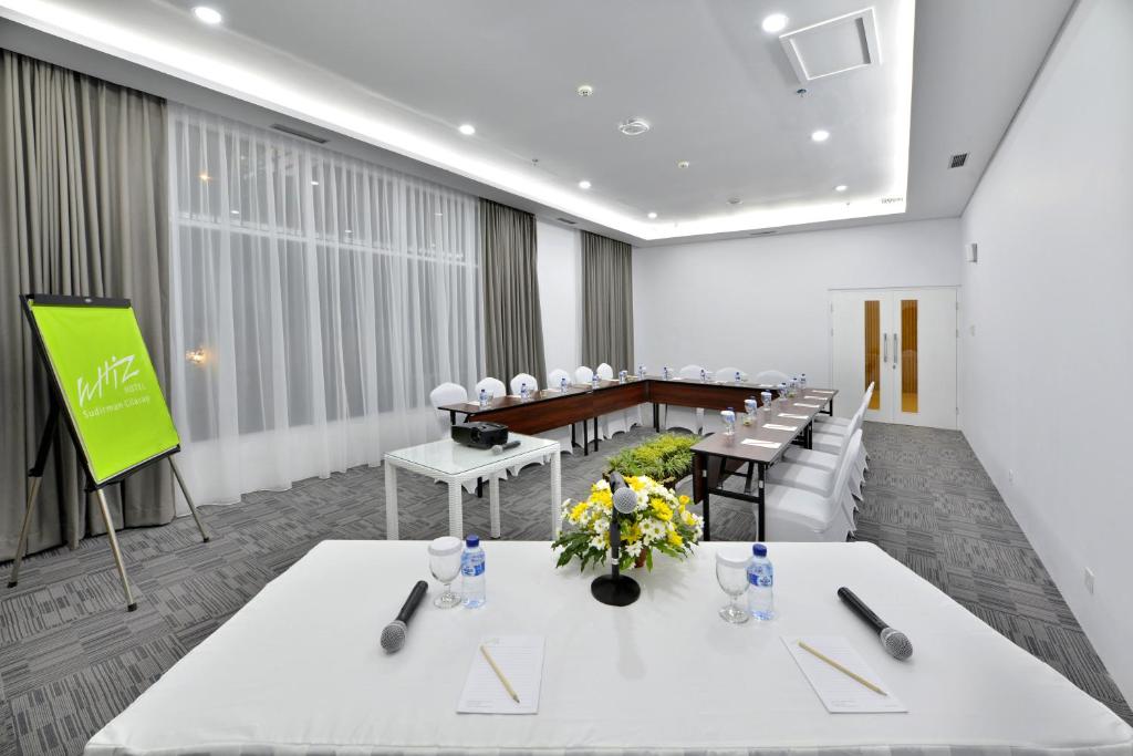 una sala conferenze con tavoli e sedie bianchi e schermo di Whiz Prime Hotel Sudirman Cilacap a Cilacap