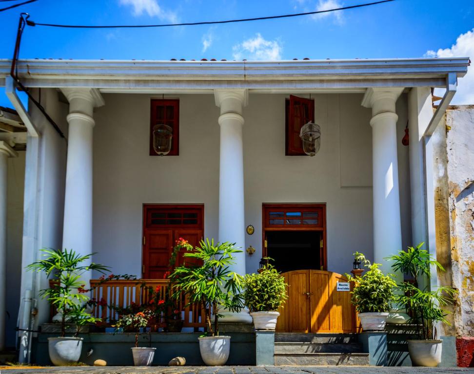 une maison avec des colonnes et des plantes en pot devant elle dans l'établissement Sirène Galle Fort, à Galle