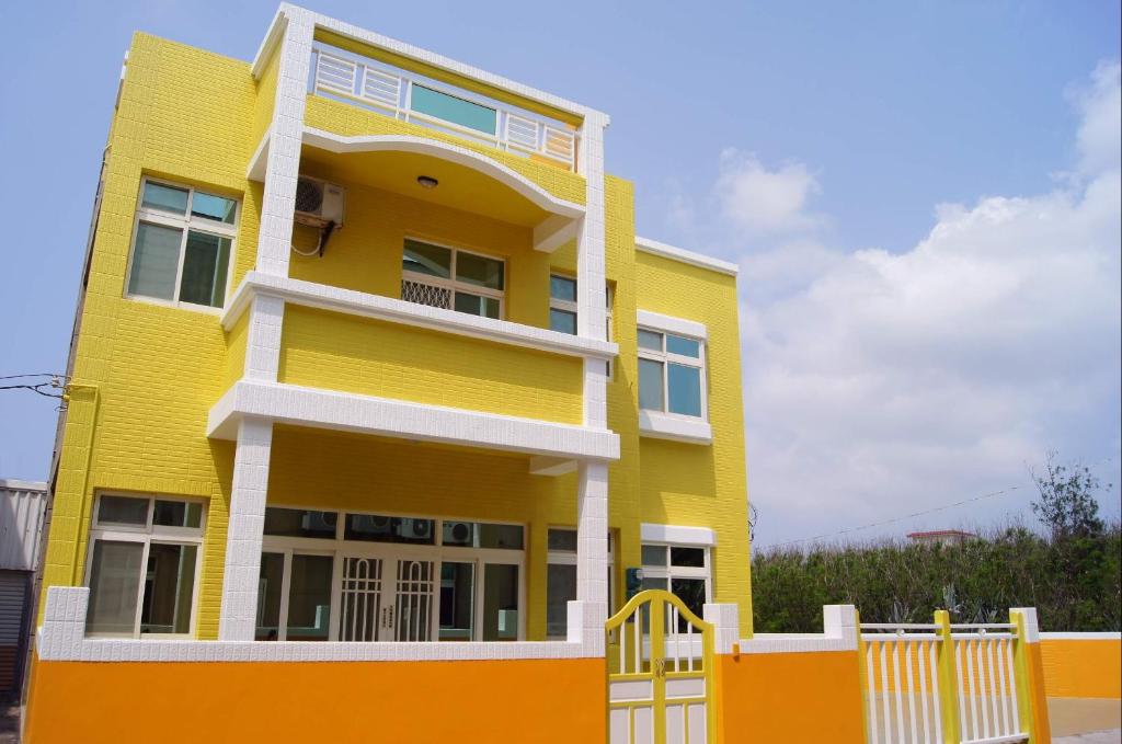 a yellow house with a white fence in front of it at Penghu Le You You Homestay in Magong