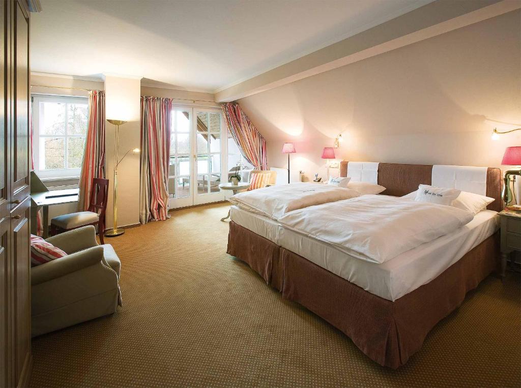 ミュンスターにあるロマンティック ホテル ホフ ツア リンデの大きなベッドと椅子が備わるホテルルームです。