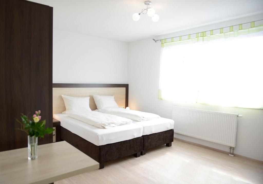 a bedroom with a bed and a table and a window at Naturparkhotel & Landgasthof Stromberg in Sachsenheim