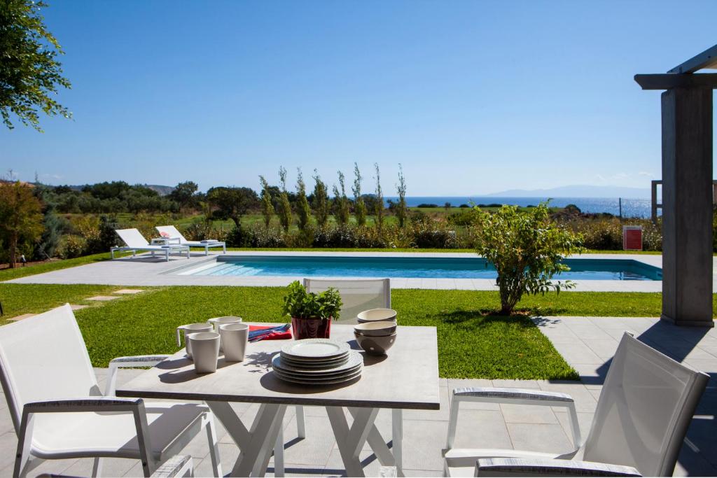 uma mesa e cadeiras brancas e uma piscina em Villa Lefteris em Svoronata