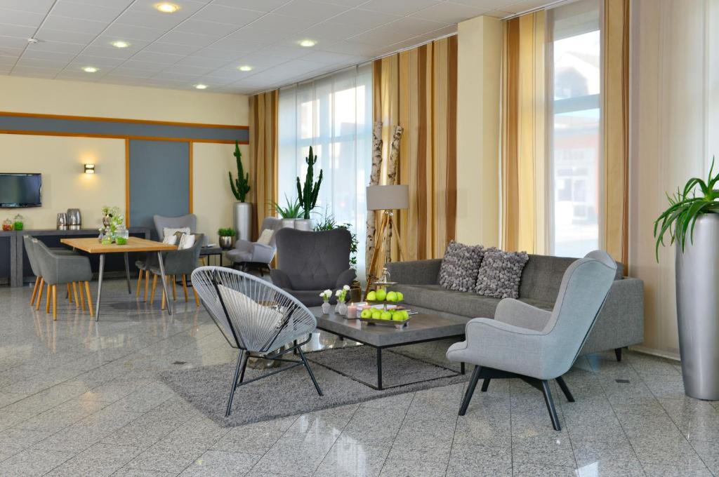 ein Wohnzimmer mit einem Sofa, Stühlen und einem Tisch in der Unterkunft Hotel Residenz Oberhausen in Oberhausen