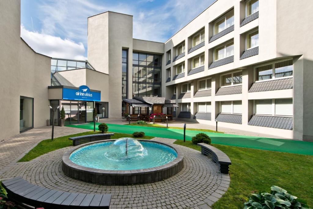 a building with a fountain in front of a building at AirInn Vilnius Hotel in Vilnius