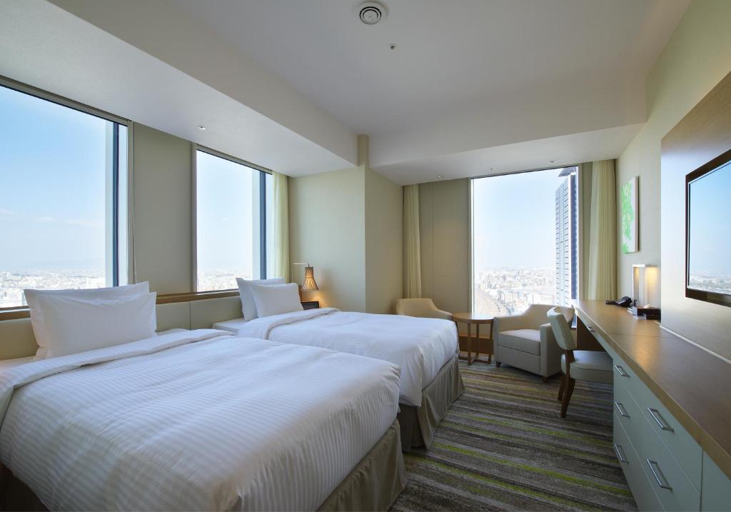 two beds in a hotel room with large windows at Nagoya JR Gate Tower Hotel in Nagoya