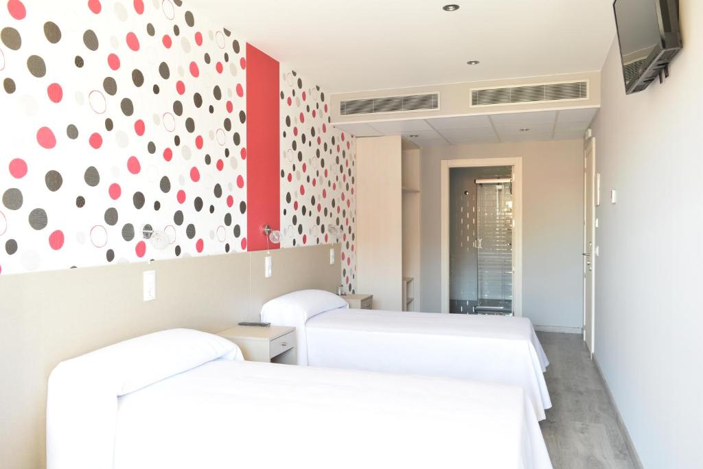 Zimmer mit 2 Betten und einer rot-weißen Wand in der Unterkunft Hotel Siskets in Torrente de Cinca