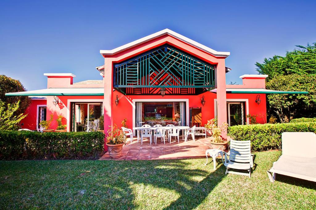 a red house with tables and chairs in the yard at Luxury Villa Golf Tenerife in Tacoronte