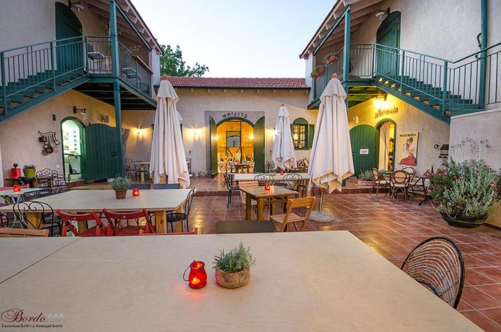 a courtyard with tables and chairs and white umbrellas at Zimer Baronita in Zikhron Ya'akov