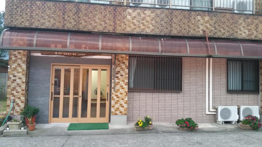 um edifício de tijolos com uma porta e flores em frente em Minshuku Toshi em Yakushima