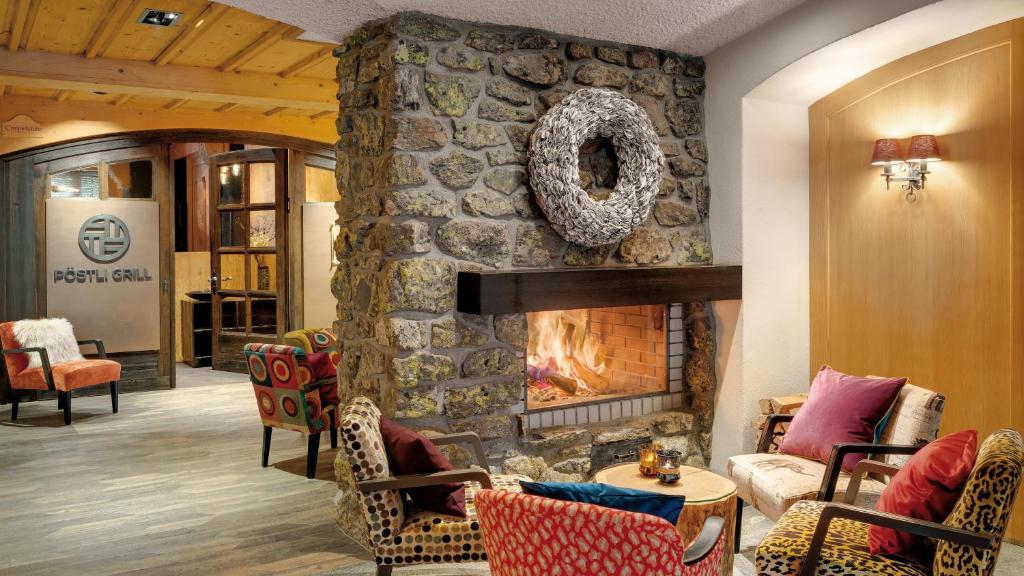 una chimenea de piedra en la sala de estar con una pared de piedra. en Morosani Posthotel en Davos