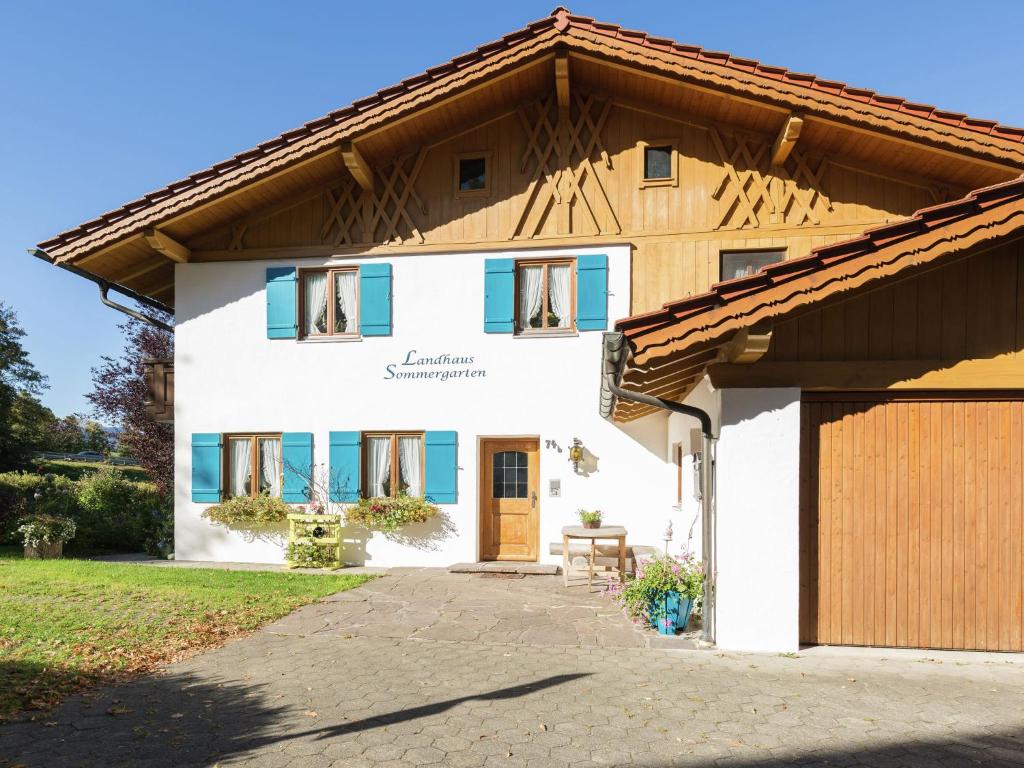 a white house with blue windows and a garage at Ländliche Ferienwohnung, Bad Bayersoien in Bad Bayersoien
