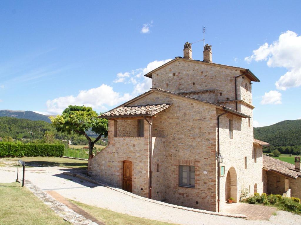 コルチャーノにあるBeautiful Holiday Home in Corciano Umbria with Swimming Poolの木を背景にした古い石造りの建物