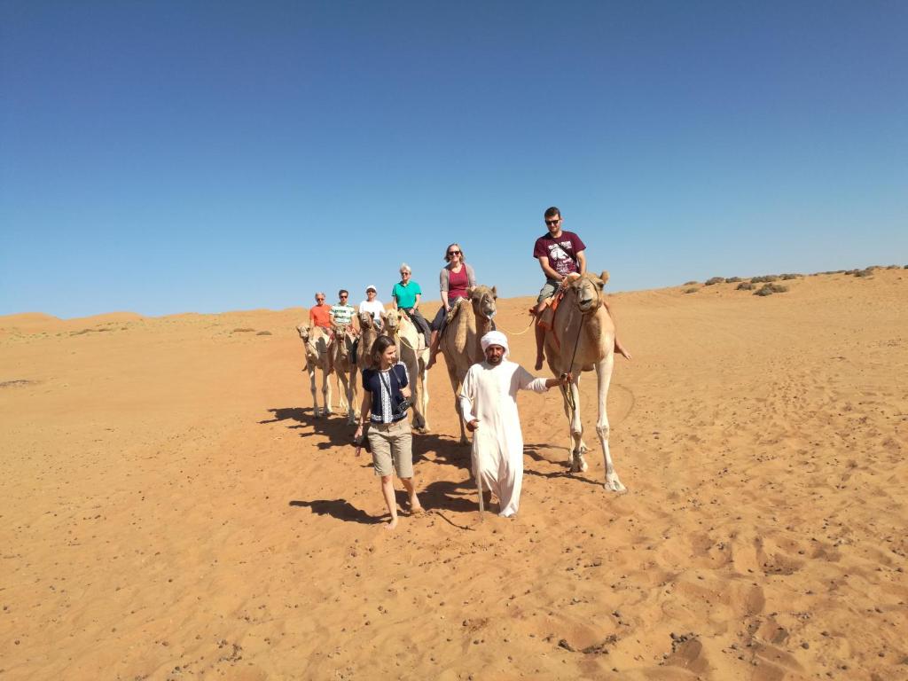 Un gruppo di persone che cavalca un cammello nel deserto di Desert Retreat Camp ad Al Wāşil