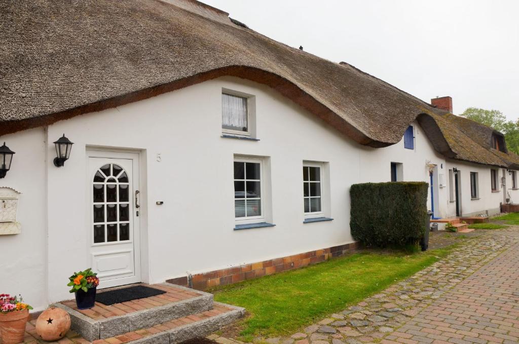 Ce cottage blanc est doté d'un toit de chaume. dans l'établissement Fewo Fischerhus, à Zempin