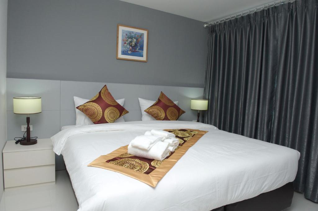 Un dormitorio con una cama blanca con toallas. en Top High Airport Link Hotel, Bangkok en Bangkok