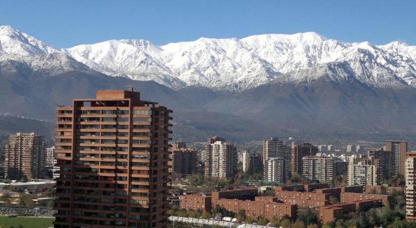 una ciudad con montañas cubiertas de nieve en el fondo en Puerta Arauco Apartamentos, en Santiago