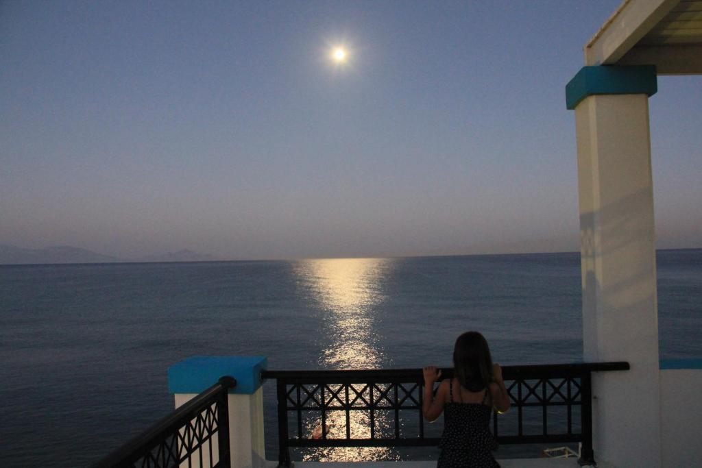 uma mulher olhando para a lua sobre o oceano em Ostria View em Kardamaina