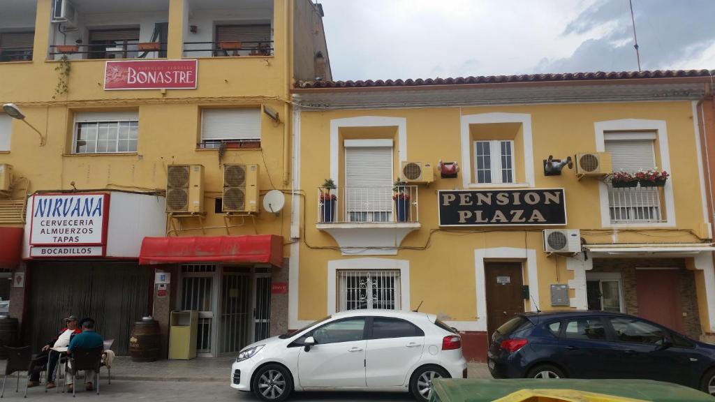 Pension Plaza في Quinto: سيارة بيضاء متوقفة أمام مبنى أصفر
