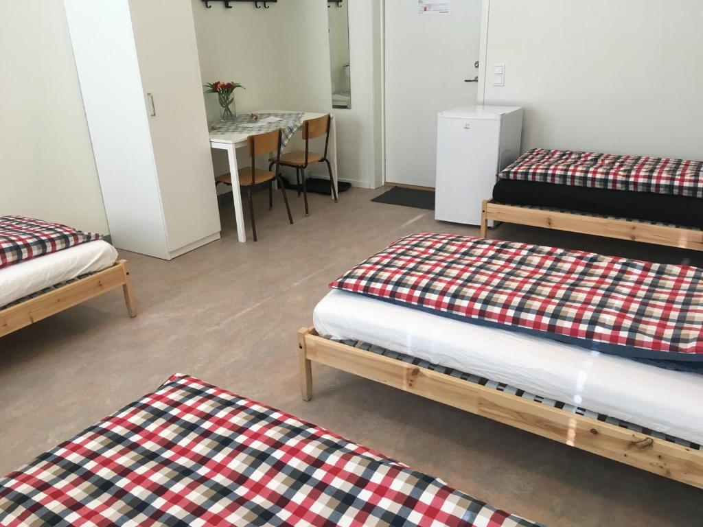 Hostel Finnmyrten في Juoksengi: غرفة بثلاث اسرة وطاولة