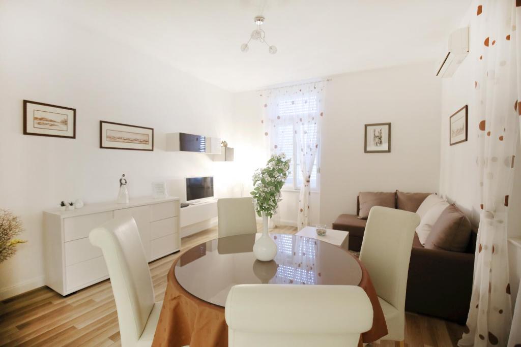 una sala de estar blanca con mesa y sillas en Bay View Apartment, en Zadar