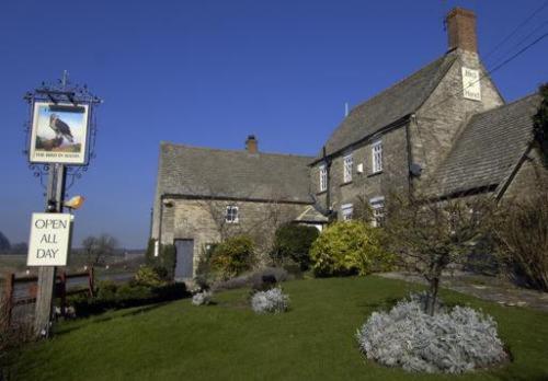 uma grande casa de pedra com uma placa no quintal em The Bird In Hand Inn, Witney em Witney