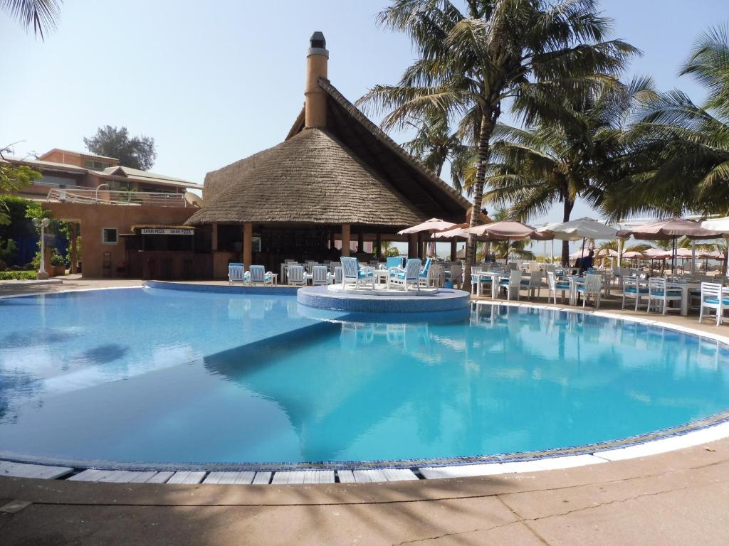 uma grande piscina com cadeiras e um edifício em Safari Village - Case73 em Saly Portudal