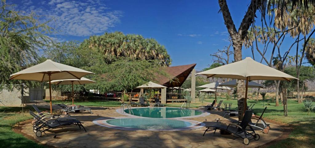 a pool with chairs and umbrellas in a yard at Ashnil Samburu Camp in Archers Post