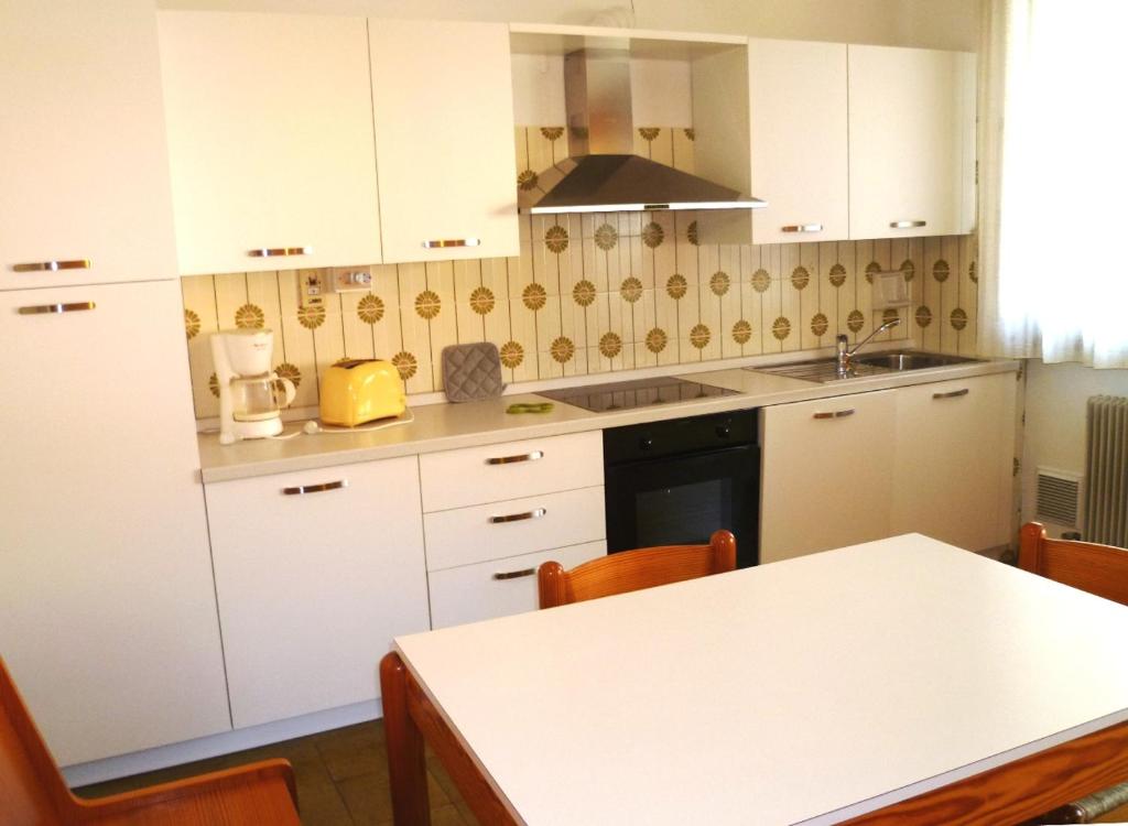 a kitchen with white cabinets and a table with chairs at Casa Lucia in Nago-Torbole