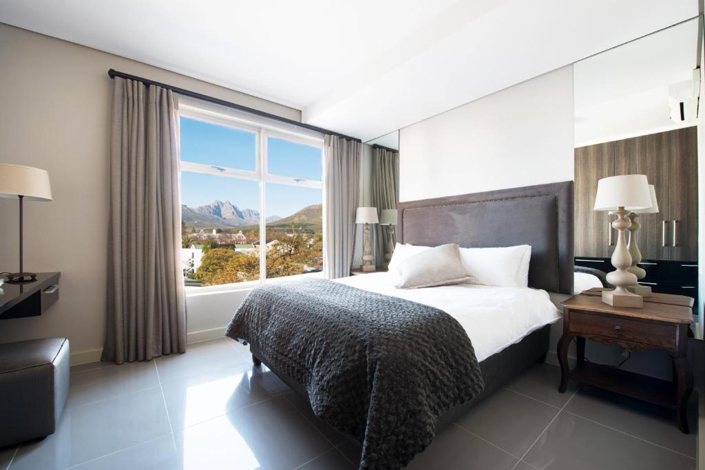 a bedroom with a bed and a large window at Lux Andringa Walk Apartments in Stellenbosch