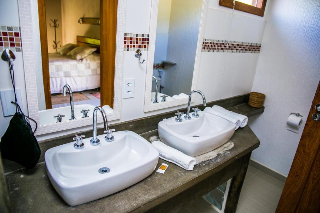 a bathroom with two sinks and two mirrors at Pousada Maritacas do Sana in Sana