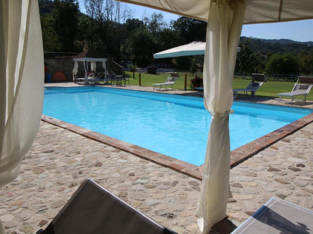 a large blue swimming pool with a canopy at Belvilla by OYO Casa Rovello in Todi