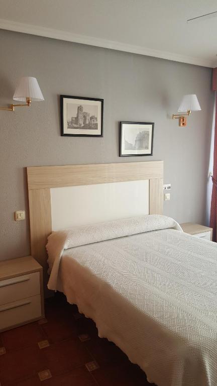 Un dormitorio con una cama y dos cuadros en la pared. en Don Diego, en Ávila