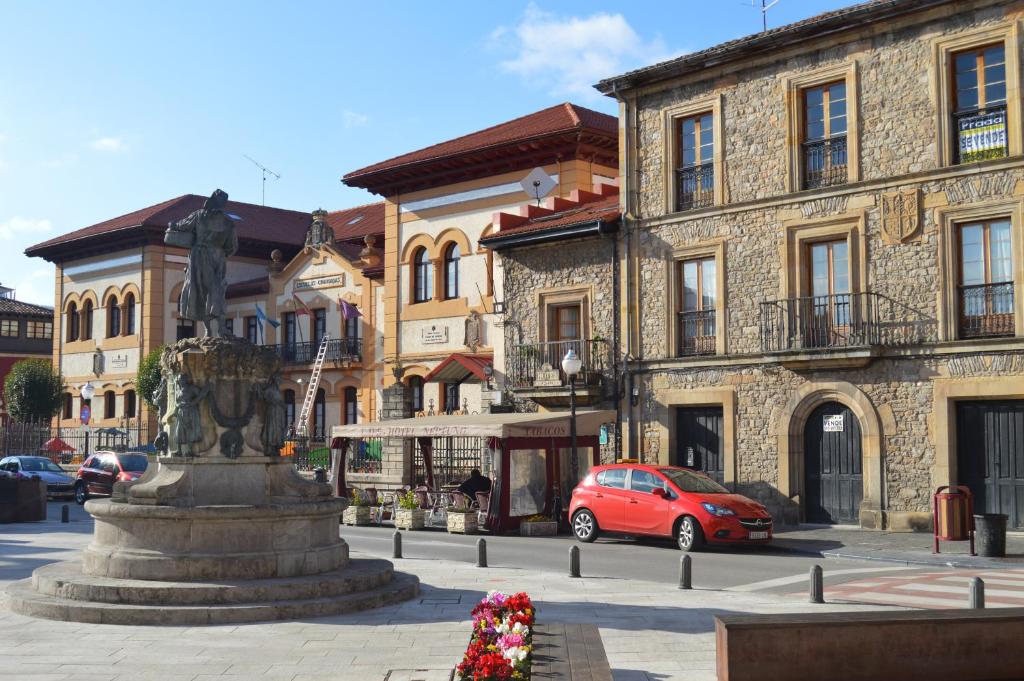a red car parked in front of a building with a fountain at Hotel Neptuno in Villaviciosa