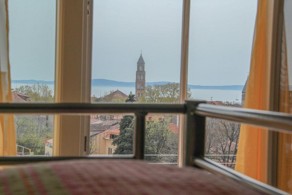 a view of a tower from a bedroom window at Backpackers Fairytale Hostel in Split