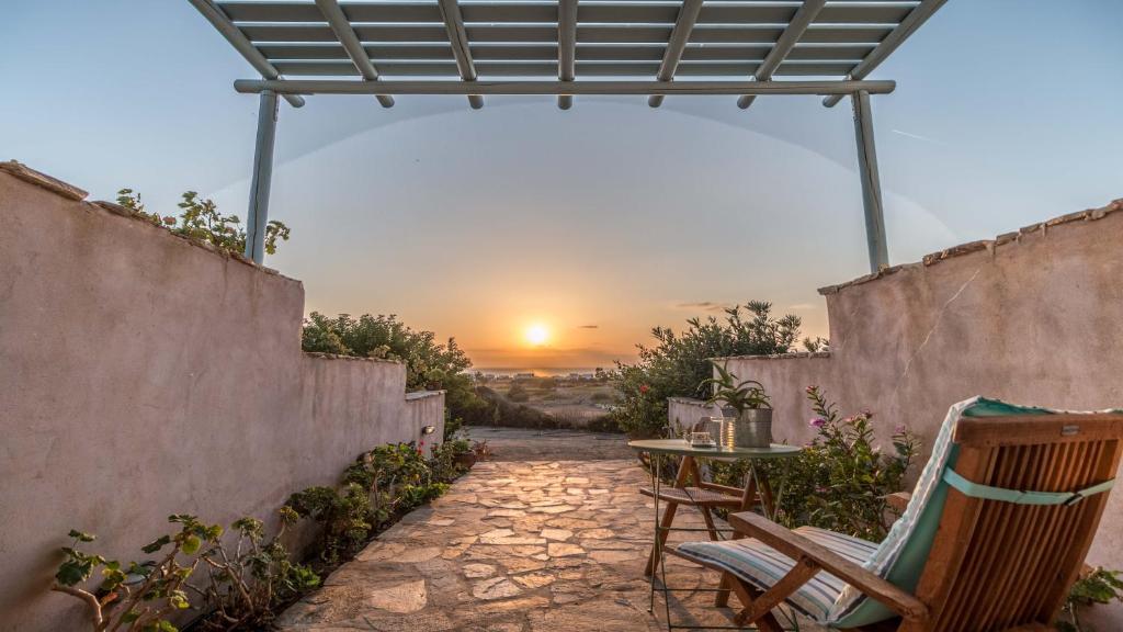 a patio with a table and chairs and a sunset at Alma Libre Villas in Kastraki