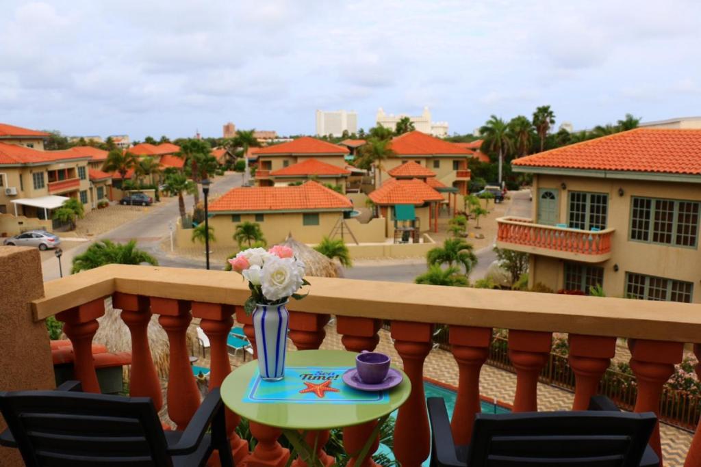 un balcón con una mesa con un jarrón de flores en Palma Real Apartment, en Palm-Eagle Beach